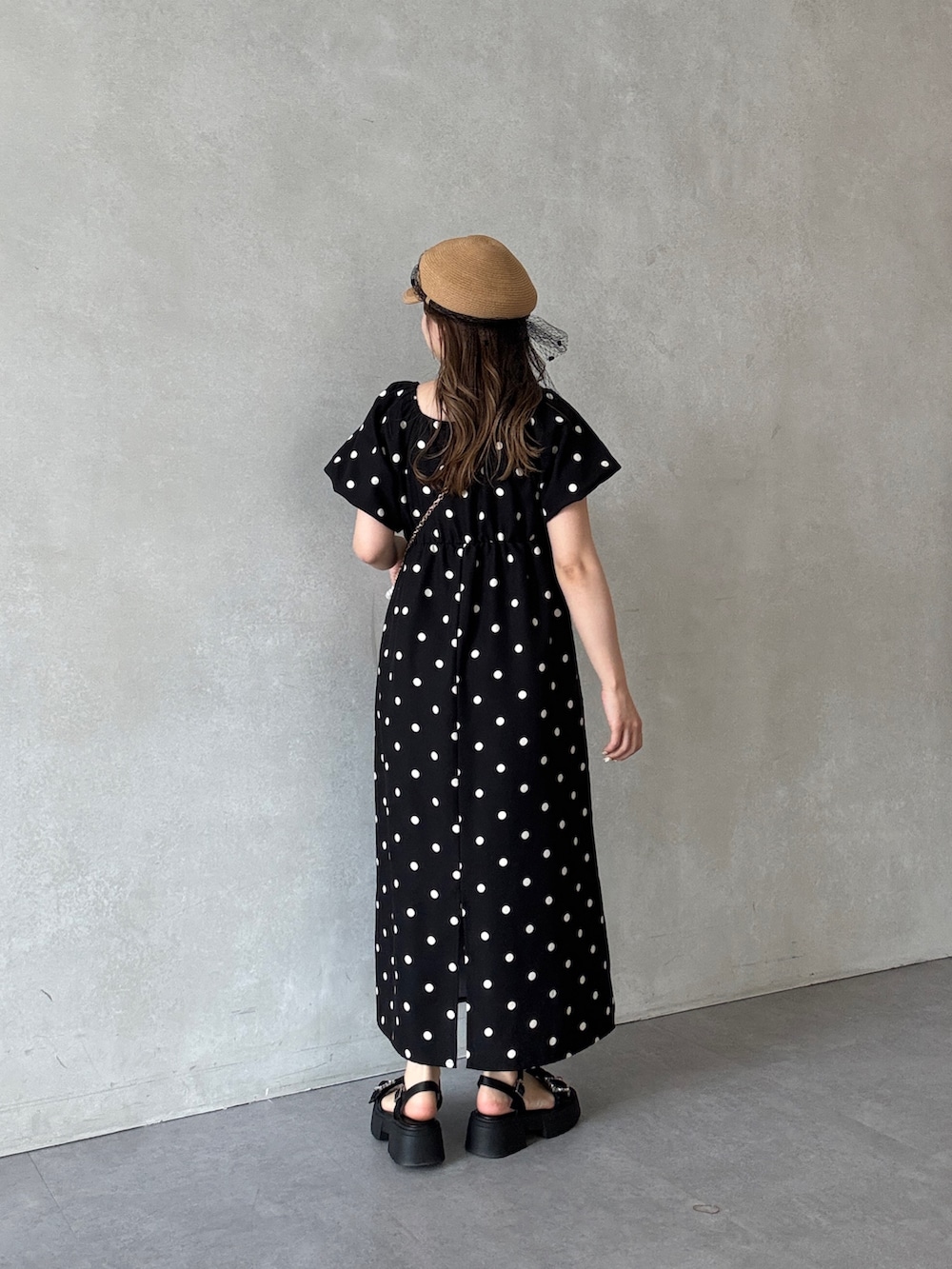 ブラック系のワンピース、ベージュ系のショルダーバッグ、ブラック系のサンダルを着用したレディースの春コーディネートの2枚目の写真