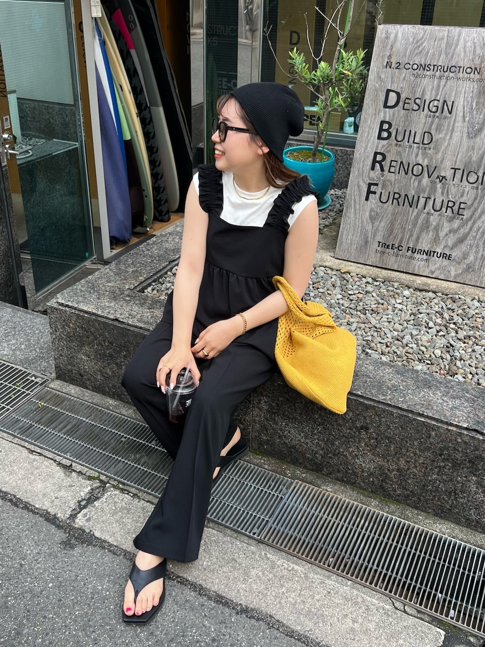 ブラック系のキャミソール、ブラック系のスラックス、イエロー系のトートバッグを着用したレディースの夏コーディネートの2枚目の写真