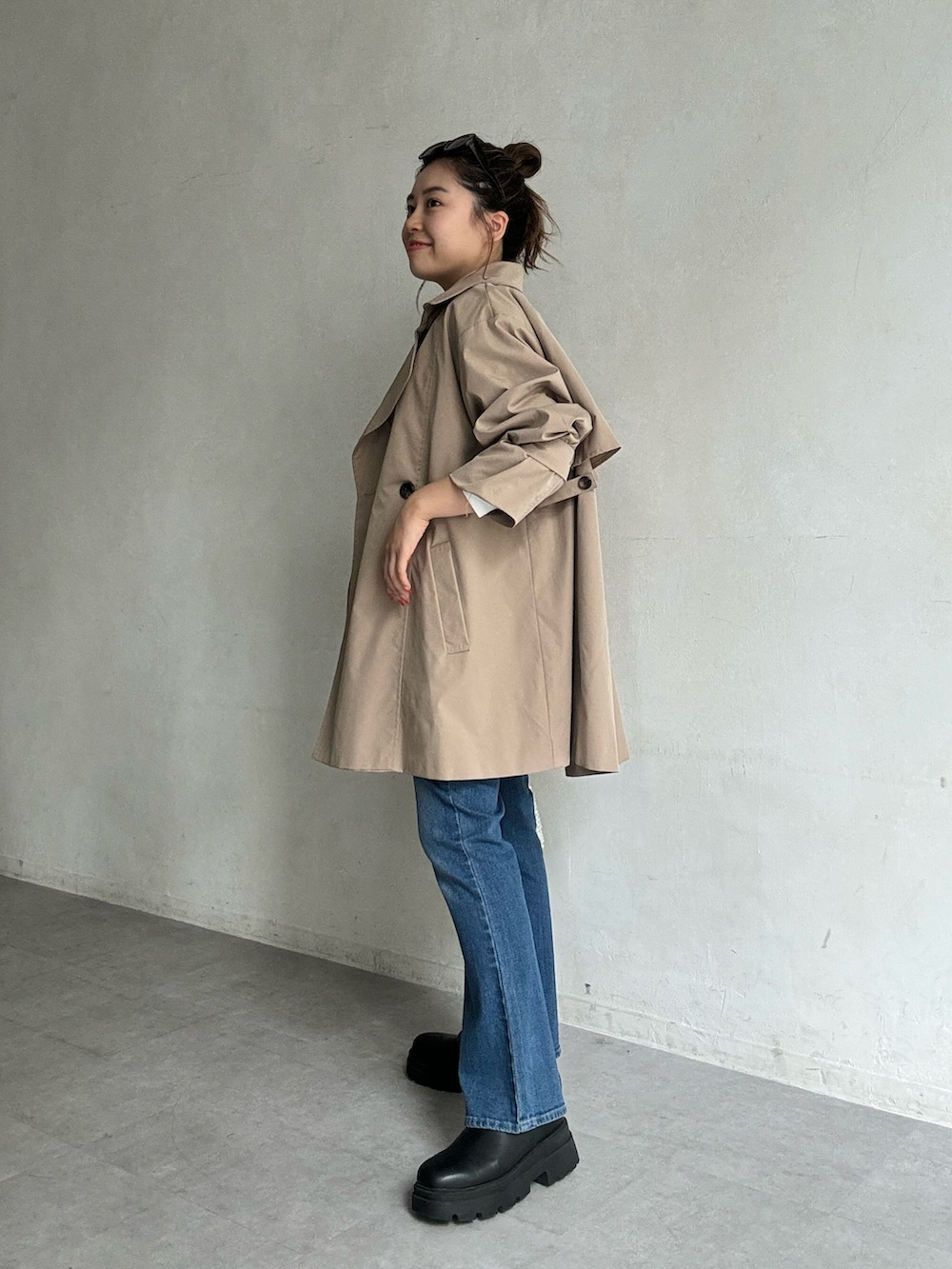 ベージュ系のトレンチコート、ブルー系のキャミソール、ブルー系のデニムパンツを着用したレディースの夏コーディネートの3枚目の写真