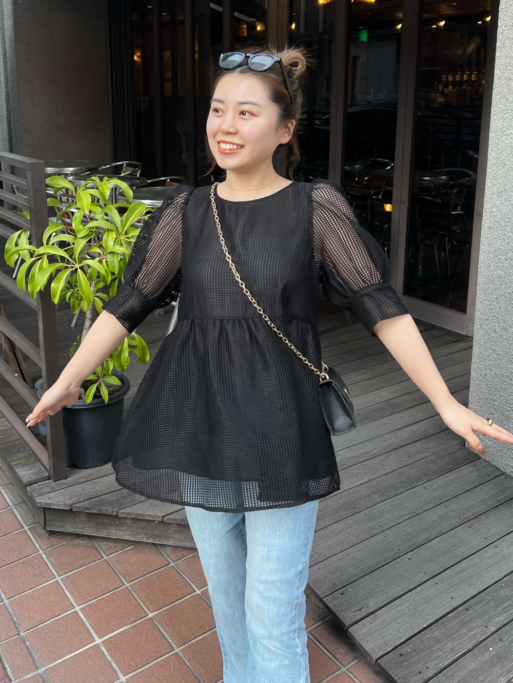 ブラック系のシャツ/ブラウス、ブルー系のデニムパンツ、ブラック系のサンダルを着用したレディースの春コーディネートの2枚目の写真