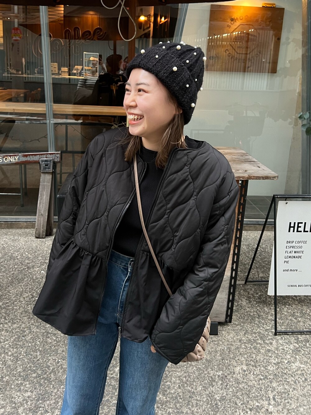 ブラック系のダウンジャケット/コート、ブルー系のデニムパンツ、ブラック系のブーツを着用したレディースの秋コーディネートの2枚目の写真