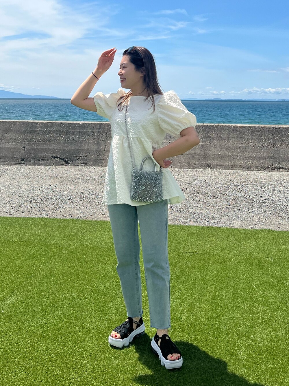 ホワイト系のシャツ/ブラウス、ブルー系のデニムパンツを着用したレディースの夏コーディネートの2枚目の写真