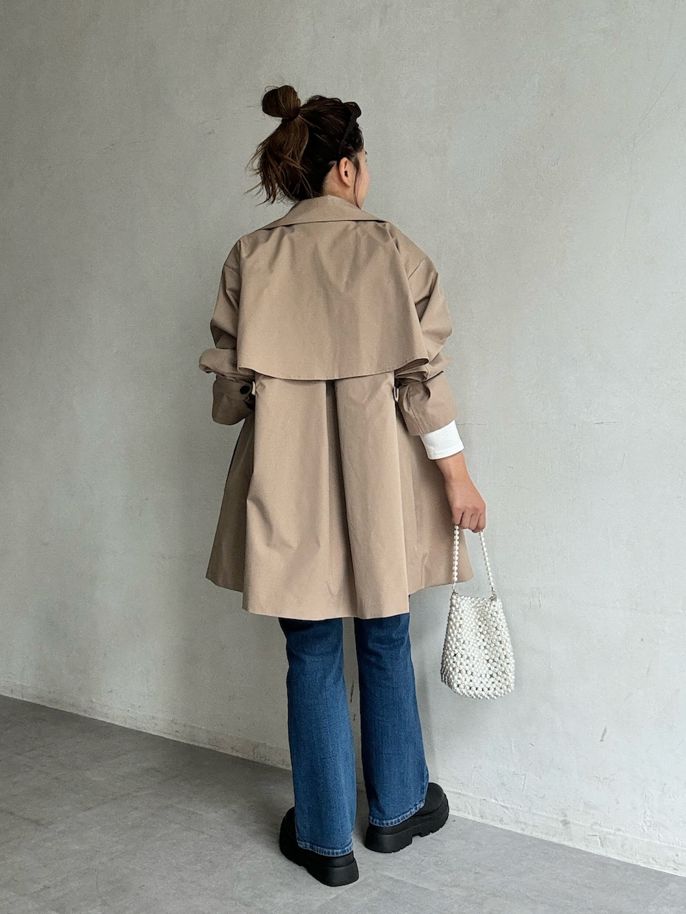 ベージュ系のトレンチコート、ブルー系のキャミソール、ブルー系のデニムパンツを着用したレディースの夏コーディネートの4枚目の写真