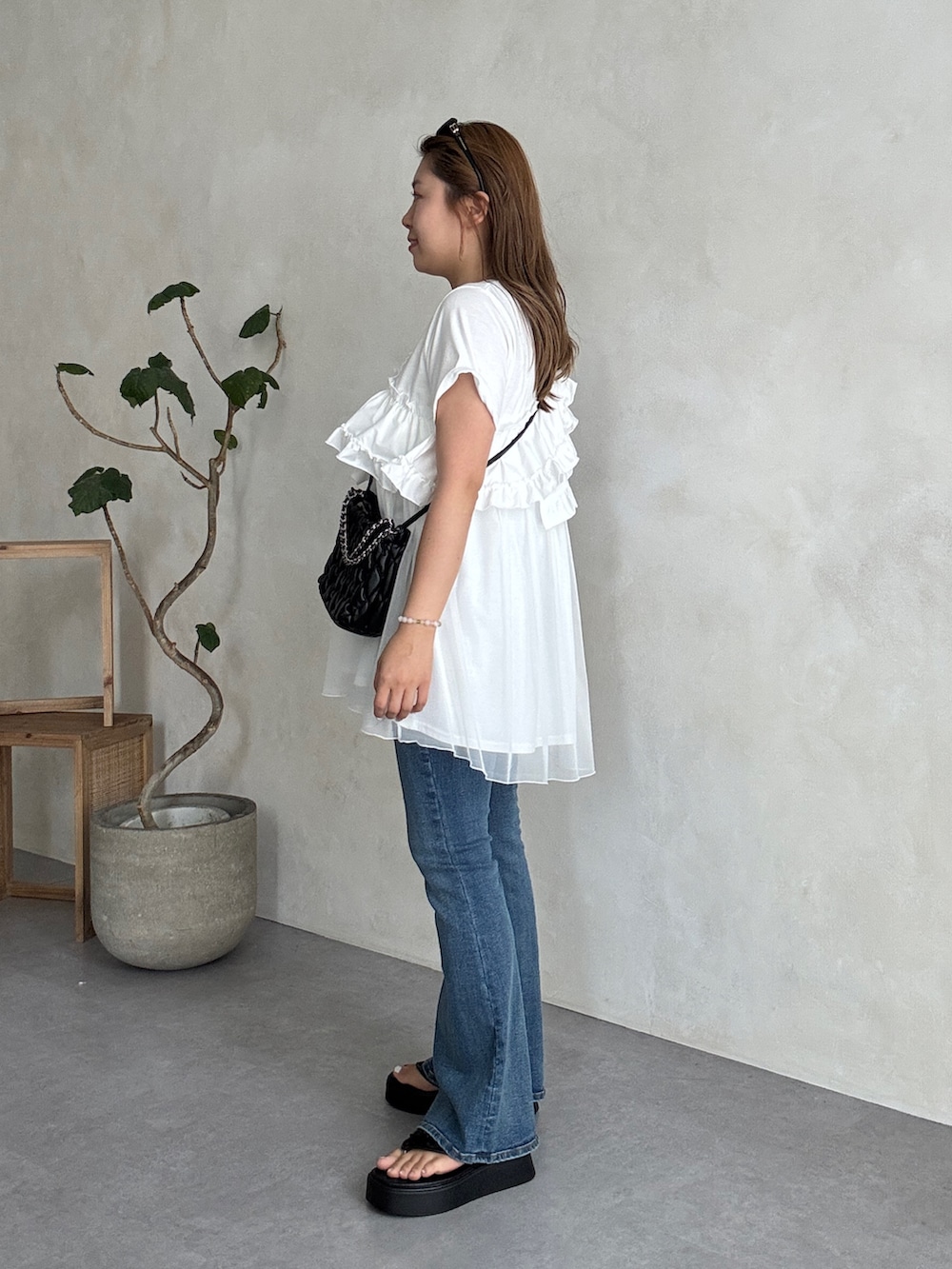 ホワイト系のTシャツ/カットソー、ブラック系のショルダーバッグ、ブルー系のデニムパンツを着用したレディースの夏コーディネートの2枚目の写真