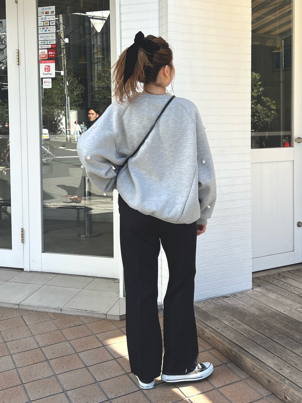 グレー系のスウェット、ブラック系のショルダーバッグ、ブラック系のスラックスを着用したレディースの冬コーディネートの3枚目の写真