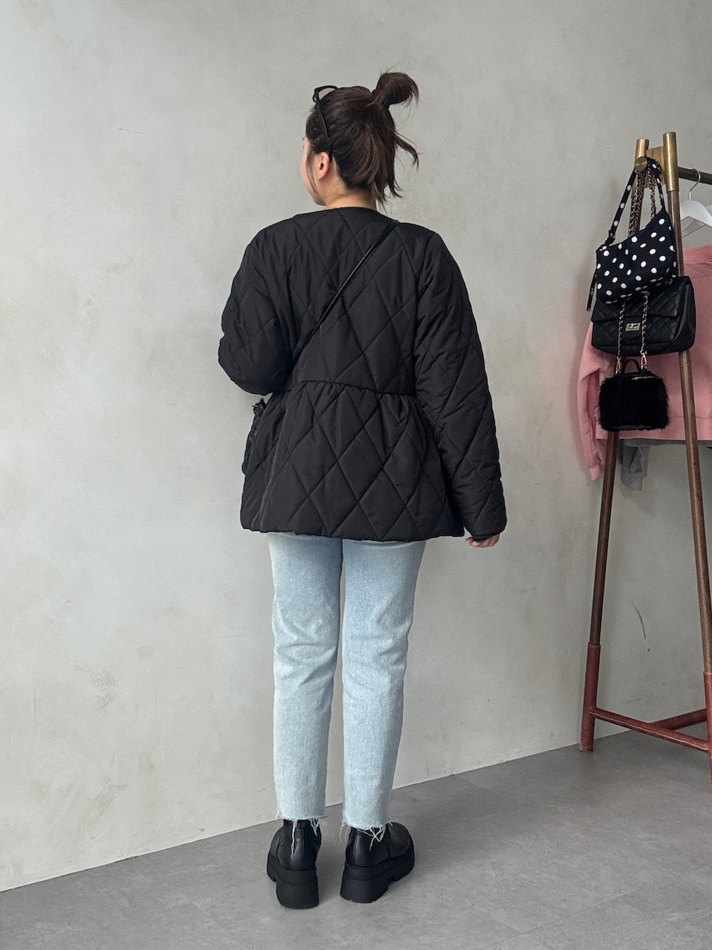 ブラック系のブルゾン、ブラック系のショルダーバッグ、ブルー系のデニムパンツを着用したレディースの秋コーディネートの3枚目の写真