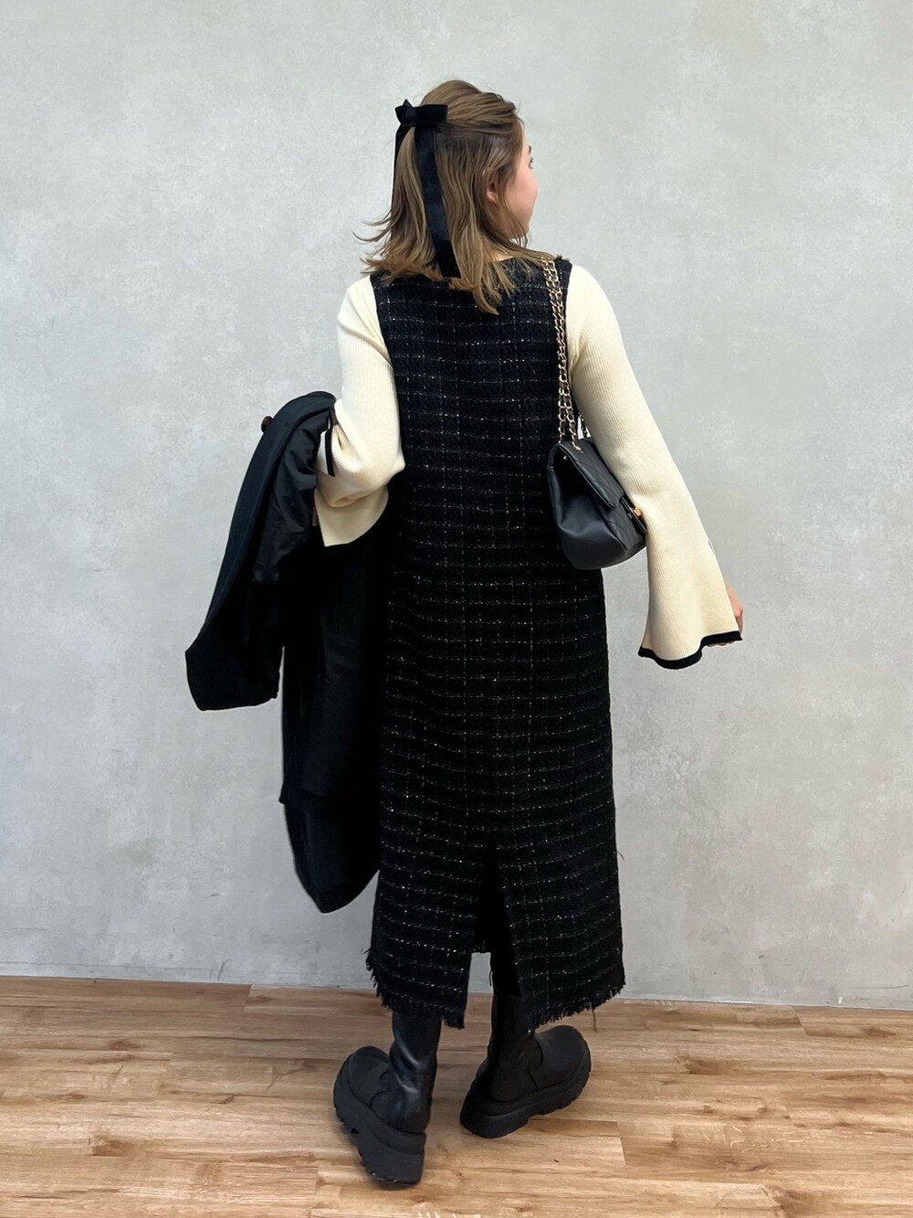 ホワイト系のニット/セーター、ブラック系のジャンパースカート、ブラック系のショルダーバッグを着用したレディースの冬コーディネートの2枚目の写真