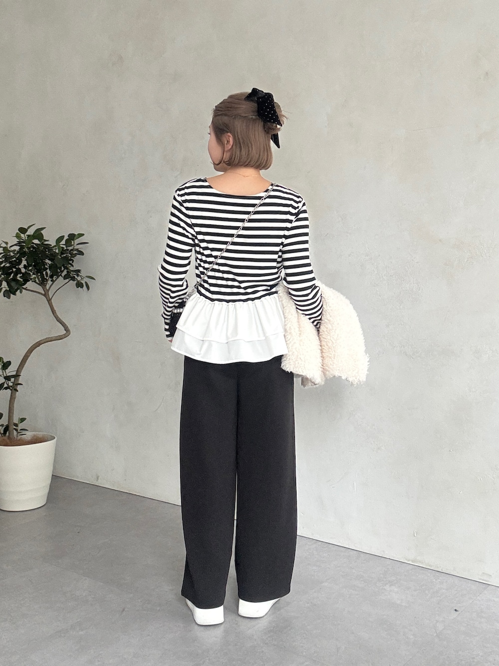 ブラック系のTシャツ/カットソー、ホワイト系のベスト、ホワイト系のスニーカーを着用したレディースの春コーディネートの4枚目の写真