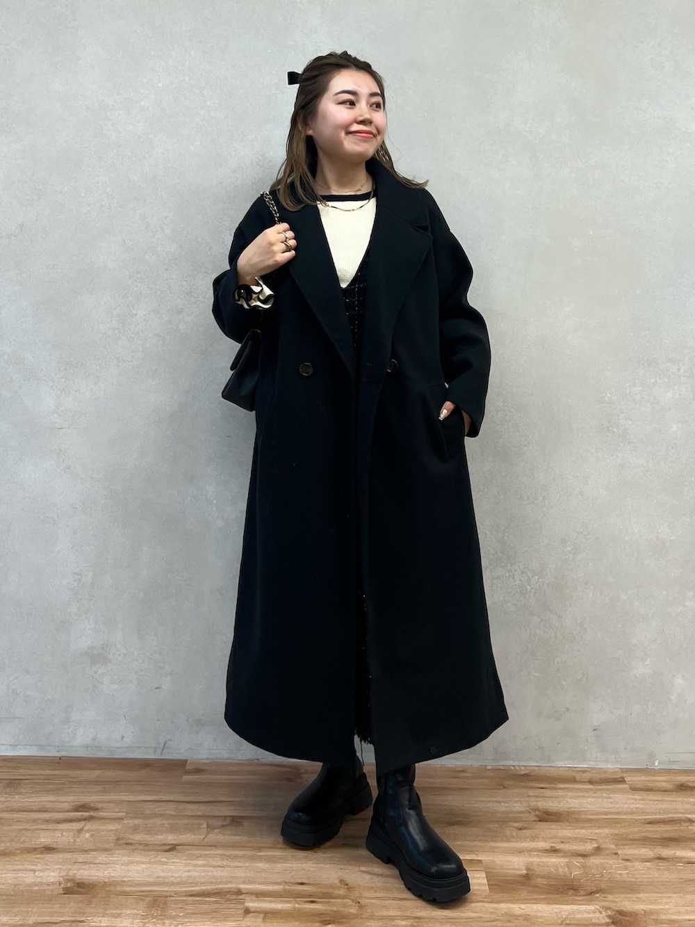 ホワイト系のニット/セーター、ブラック系のジャンパースカート、ブラック系のショルダーバッグを着用したレディースの冬コーディネートの3枚目の写真