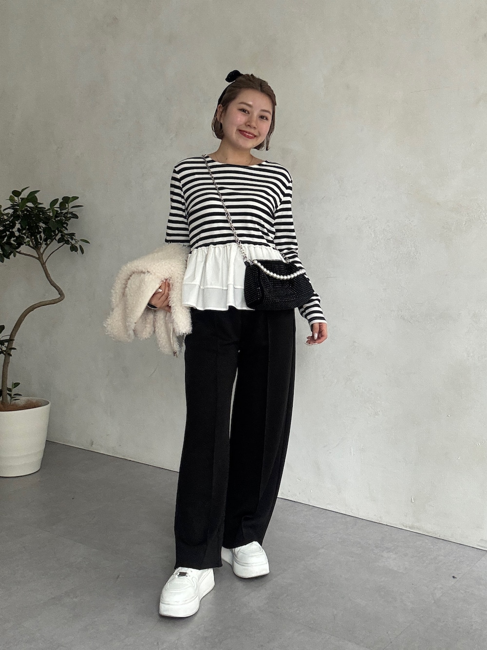 ブラック系のTシャツ/カットソー、ホワイト系のベスト、ホワイト系のスニーカーを着用したレディースの春コーディネートの2枚目の写真