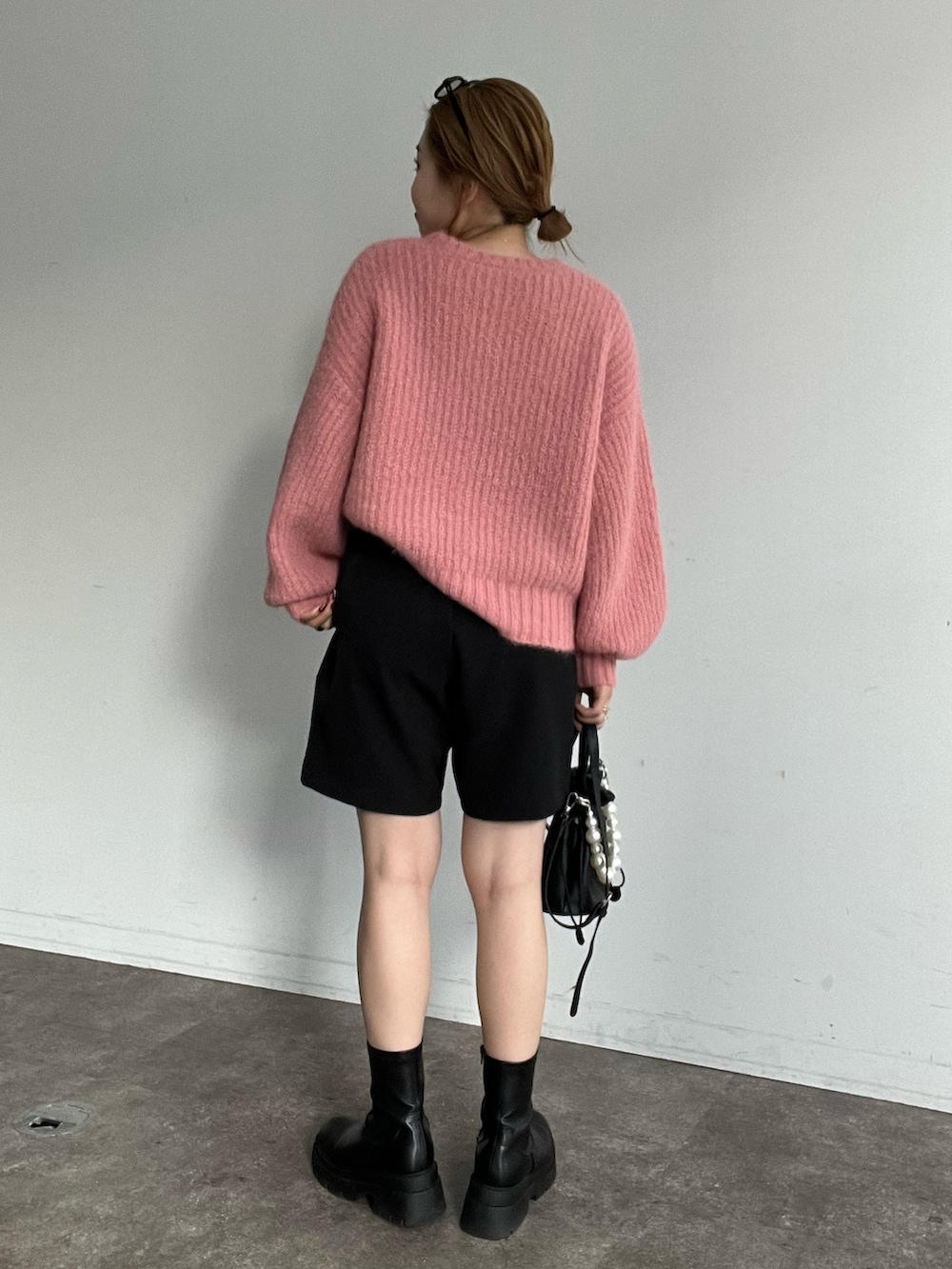 ピンク系のニット/セーター、ブラック系のその他パンツ、ブラック系のブーツを着用したレディースの秋コーディネートの2枚目の写真