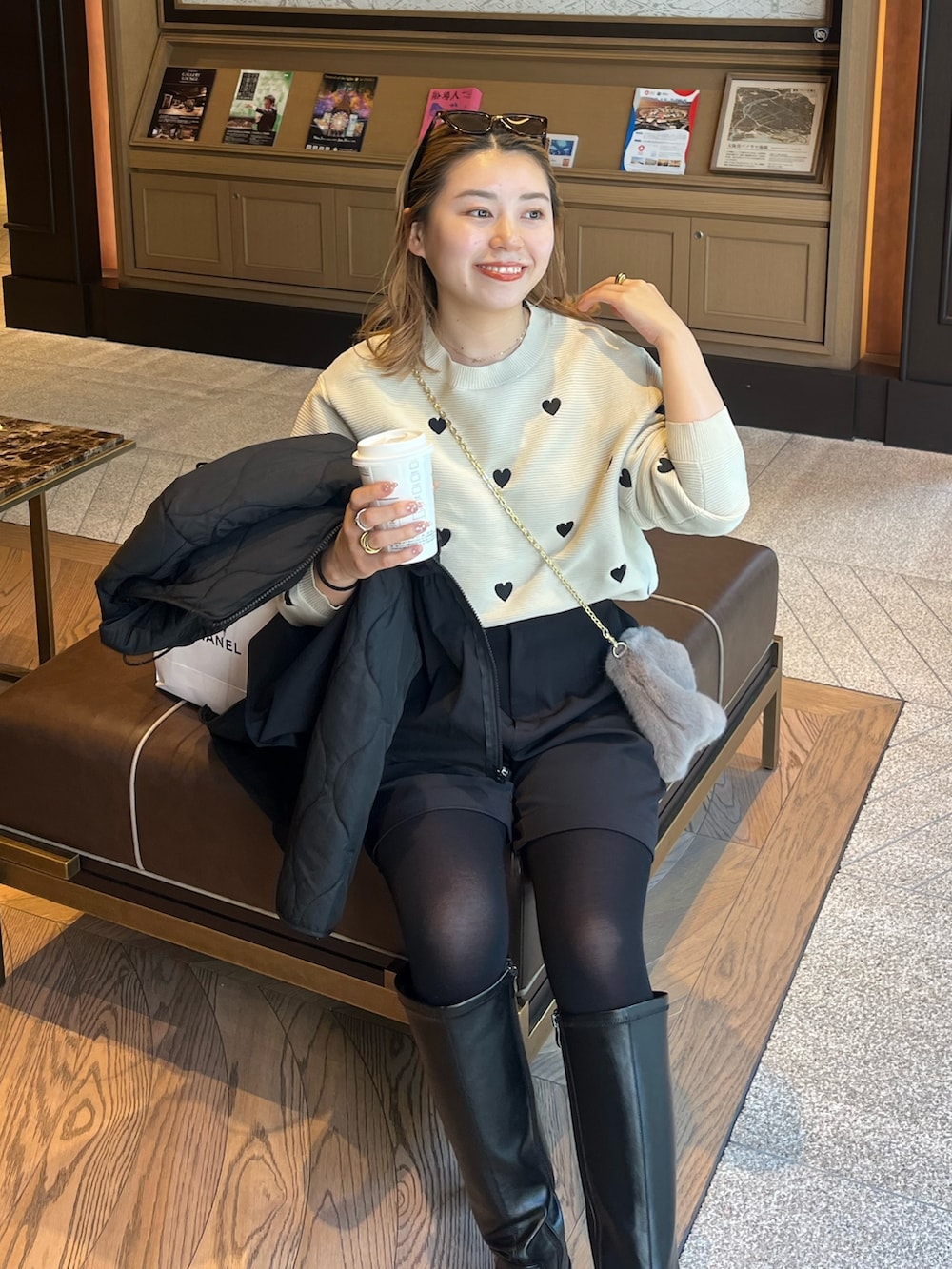 ベージュ系のニット/セーター、ブラック系のダウンジャケット/コート、ブラウン系のショルダーバッグを着用したレディースの秋コーディネートの4枚目の写真