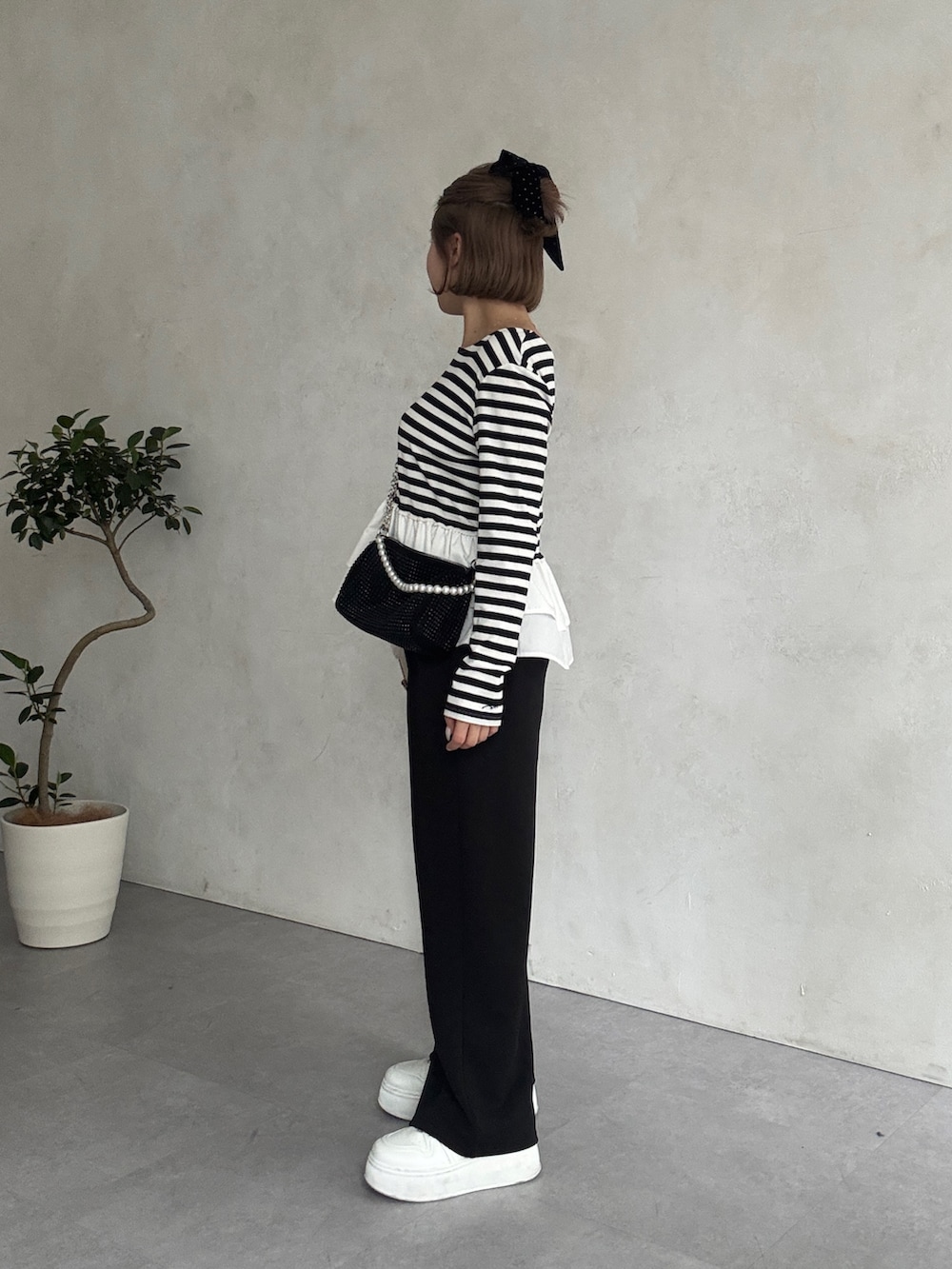 ブラック系のTシャツ/カットソー、ホワイト系のベスト、ホワイト系のスニーカーを着用したレディースの春コーディネートの3枚目の写真