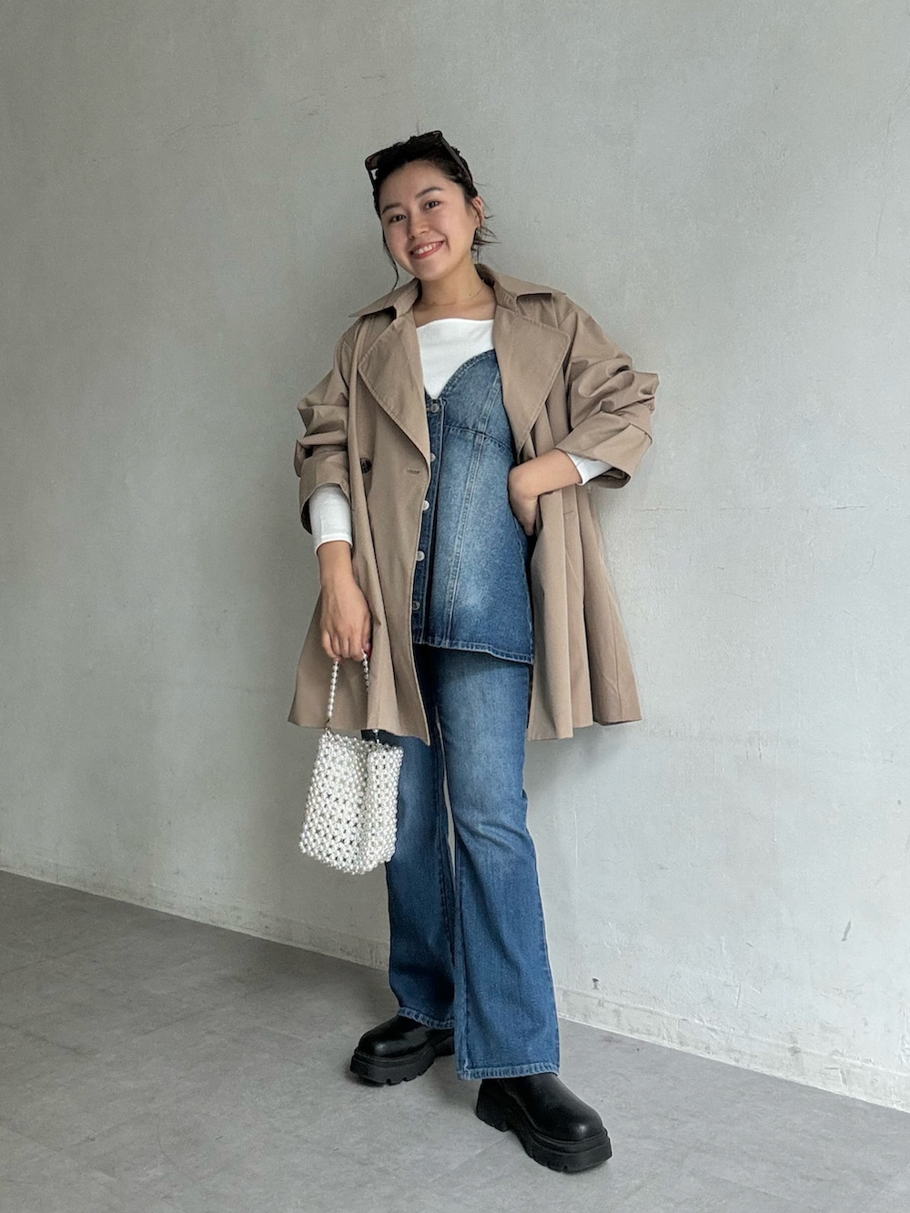ベージュ系のトレンチコート、ブルー系のキャミソール、ブルー系のデニムパンツを着用したレディースの夏コーディネートの2枚目の写真