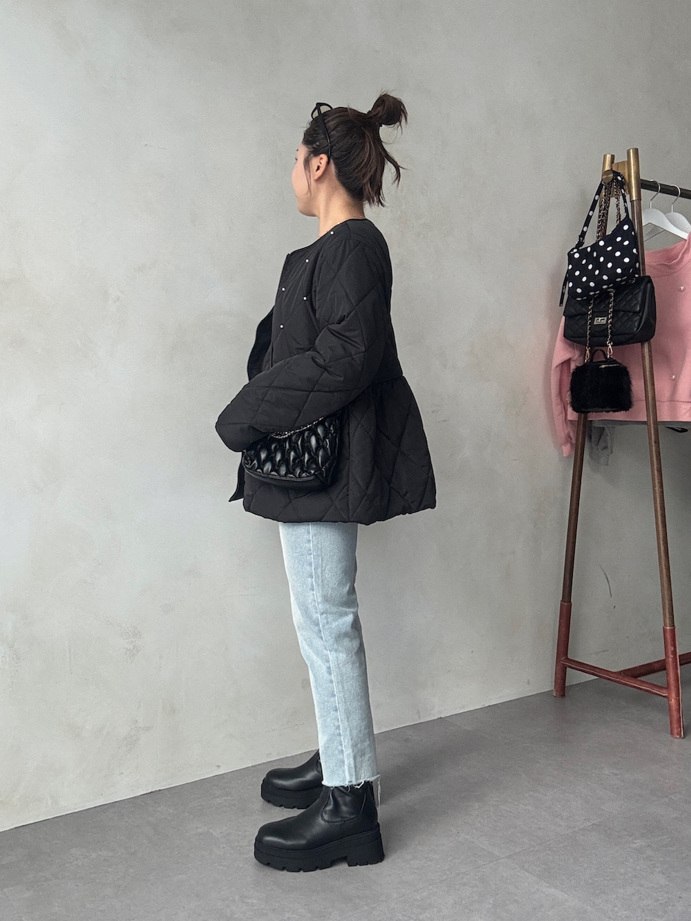 ブラック系のブルゾン、ブラック系のショルダーバッグ、ブルー系のデニムパンツを着用したレディースの秋コーディネートの2枚目の写真