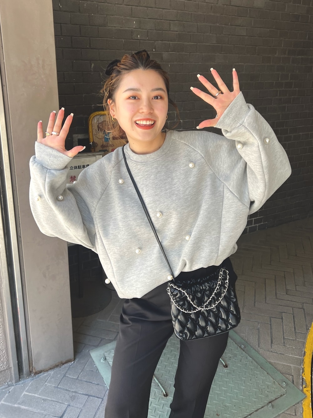 グレー系のスウェット、ブラック系のショルダーバッグ、ブラック系のスラックスを着用したレディースの冬コーディネートの2枚目の写真