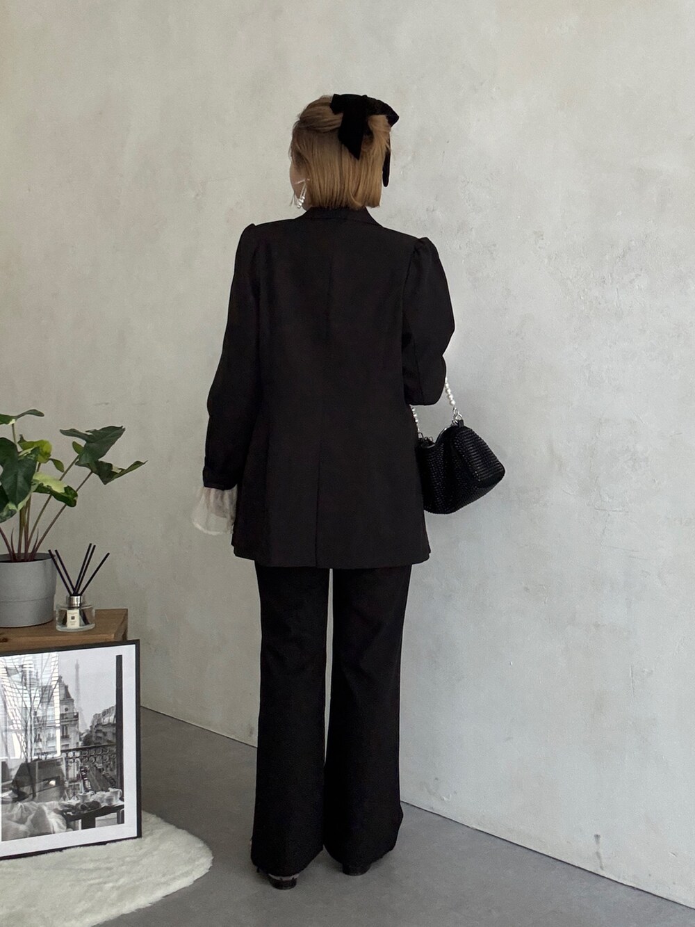 ブラック系のテーラードジャケット、ホワイト系のパンツドレス、ブラック系のショルダーバッグを着用したレディースの冬コーディネートの3枚目の写真