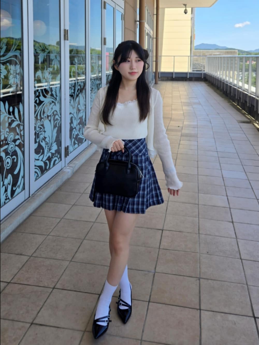 ホワイト系のニット/セーター、ブルー系のスカート、ブラック系のハンドバッグを着用したレディースの秋コーディネートの4枚目の写真