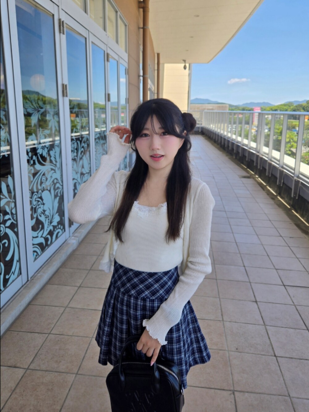 ホワイト系のニット/セーター、ブルー系のスカート、ブラック系のハンドバッグを着用したレディースの秋コーディネートの5枚目の写真