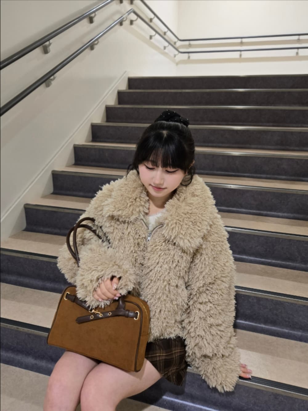 ベージュ系のブルゾン、ブラウン系のスカート、イエロー系のハンドバッグを着用したレディースの冬コーディネートの2枚目の写真