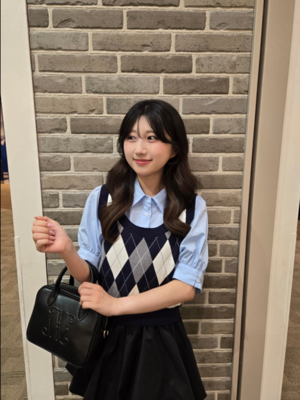 ブルー系のシャツ/ブラウス、ブラック系のハンドバッグ、ブラック系のスカートを着用したレディースの夏コーディネートの2枚目の写真