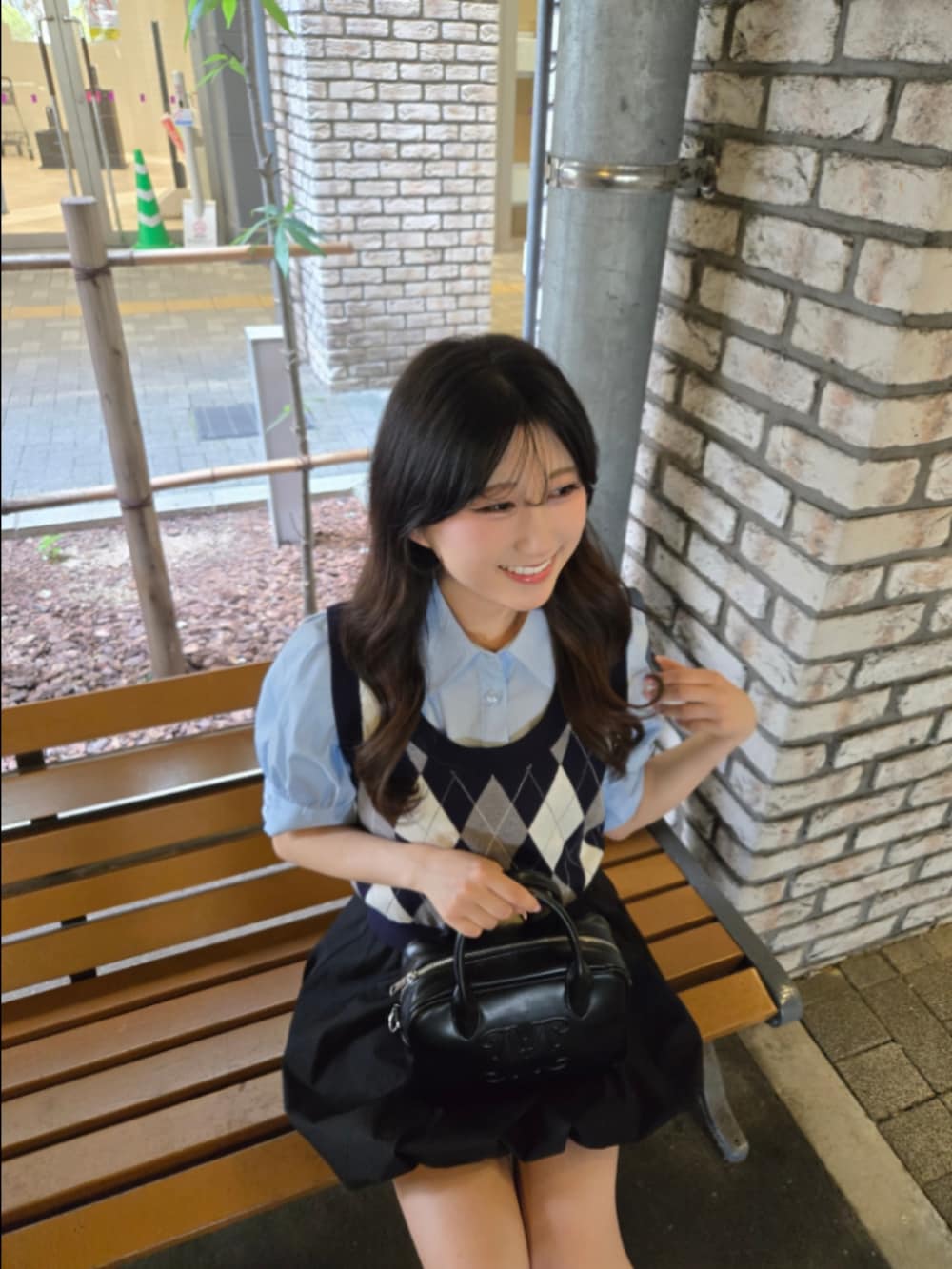 ブルー系のシャツ/ブラウス、ブラック系のハンドバッグ、ブラック系のスカートを着用したレディースの夏コーディネートの4枚目の写真