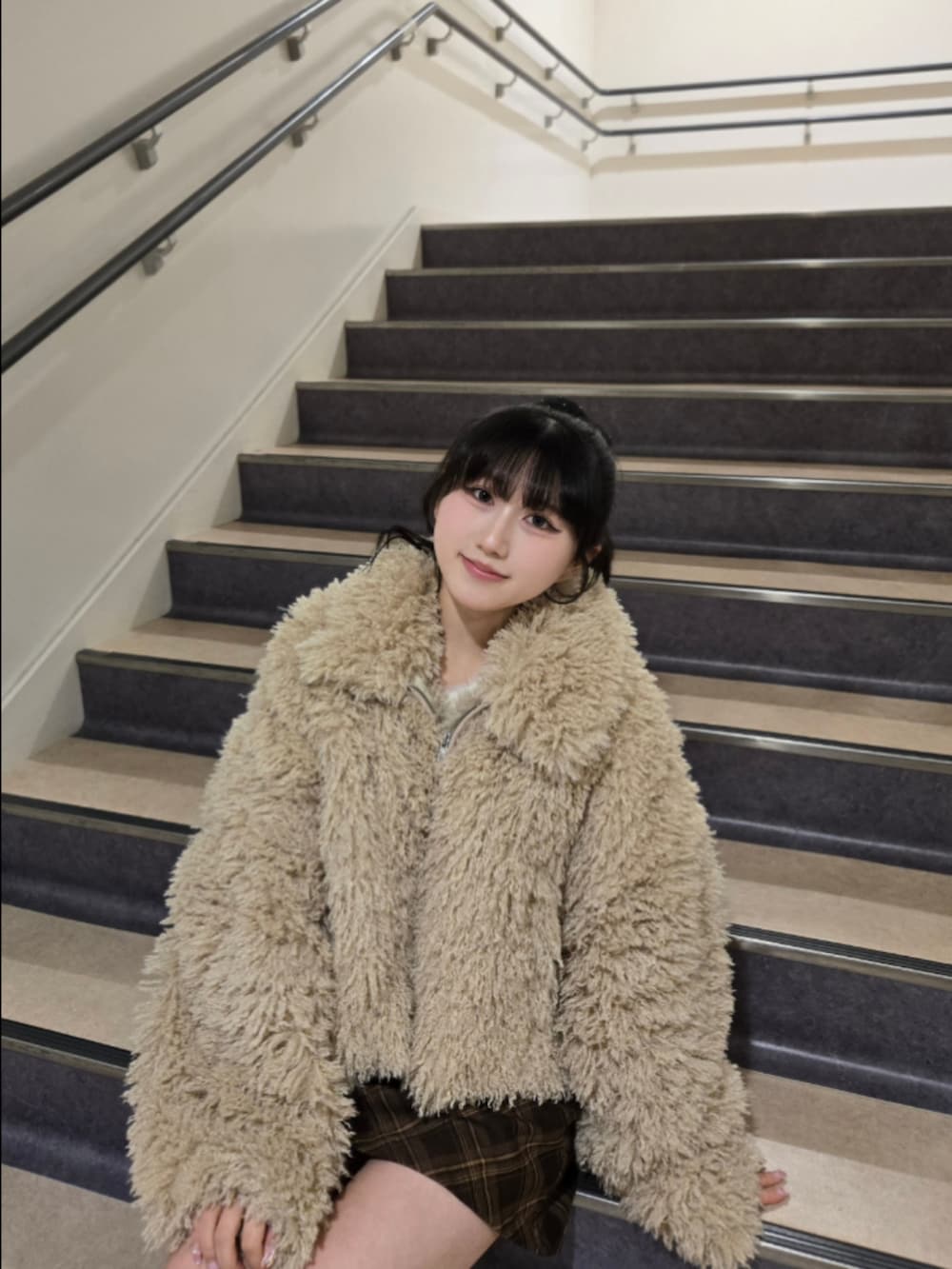 ベージュ系のブルゾン、ブラウン系のスカート、イエロー系のハンドバッグを着用したレディースの冬コーディネートの4枚目の写真