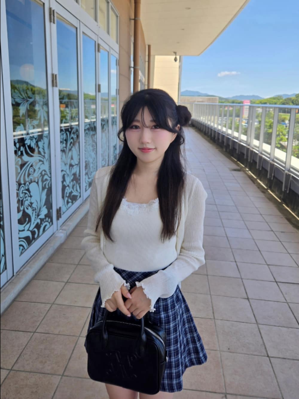 ホワイト系のニット/セーター、ブルー系のスカート、ブラック系のハンドバッグを着用したレディースの秋コーディネートの3枚目の写真