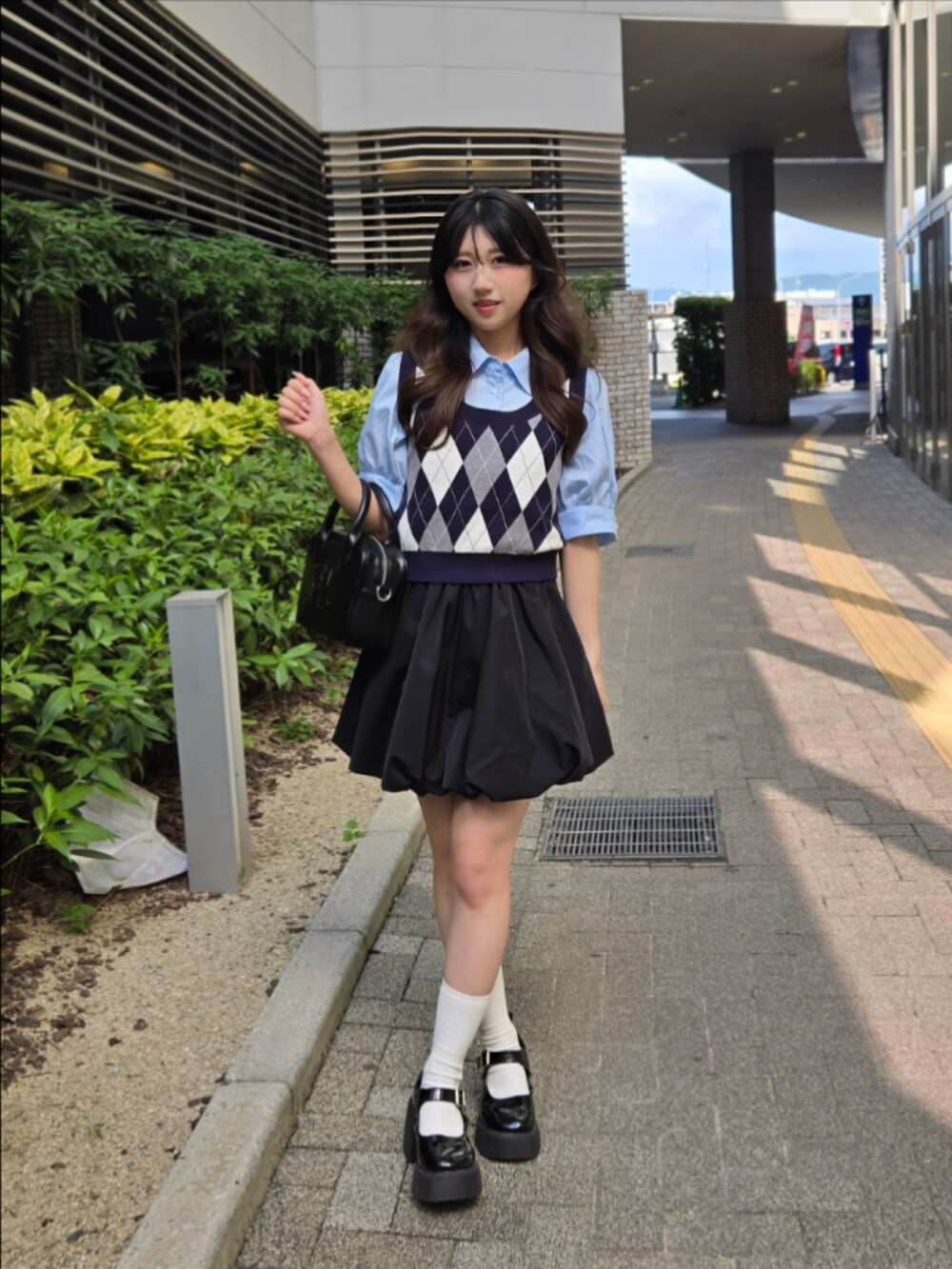 ブルー系のシャツ/ブラウス、ブラック系のハンドバッグ、ブラック系のスカートを着用したレディースの夏コーディネートの3枚目の写真