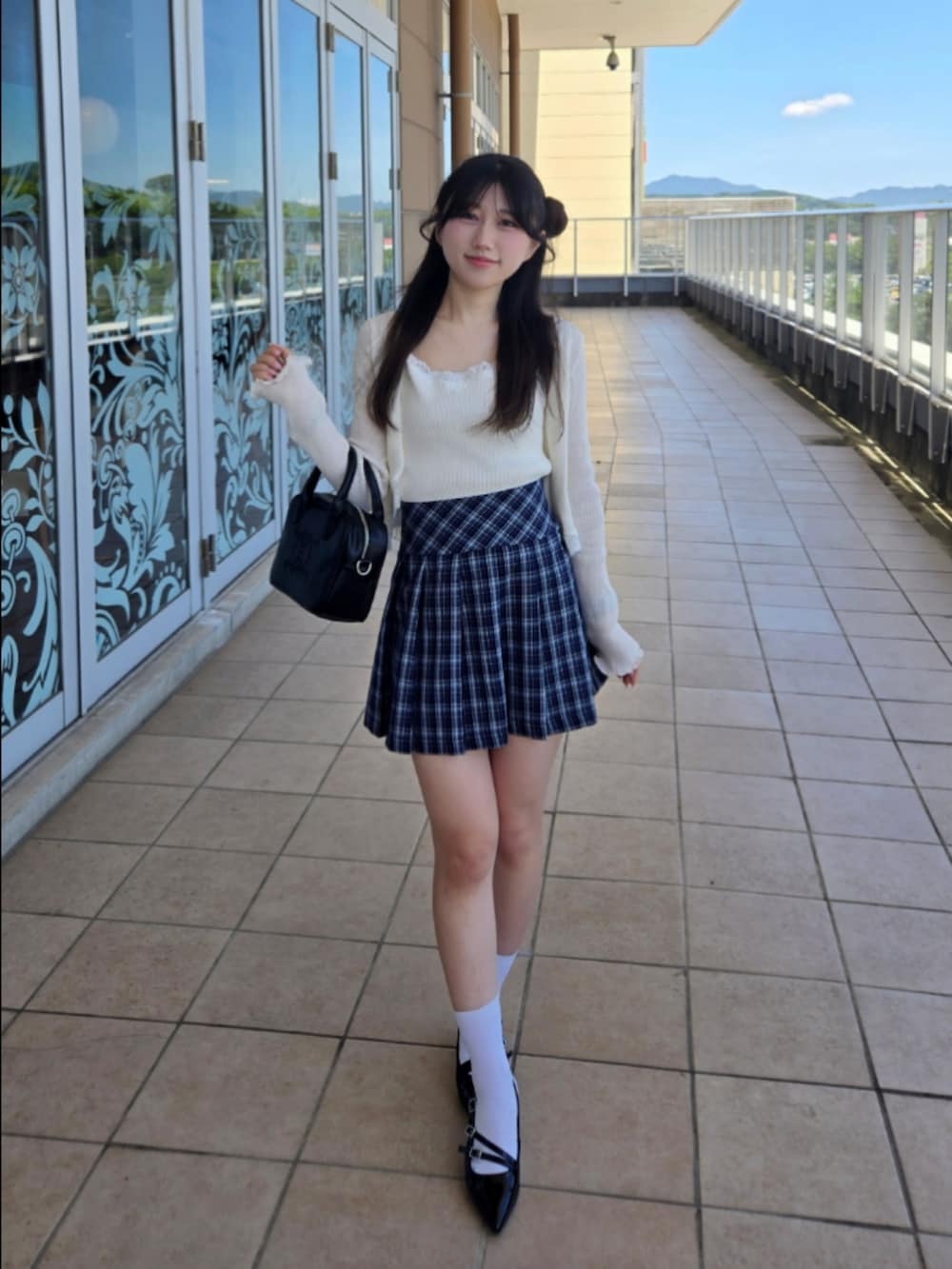 ホワイト系のニット/セーター、ブルー系のスカート、ブラック系のハンドバッグを着用したレディースの秋コーディネートの2枚目の写真