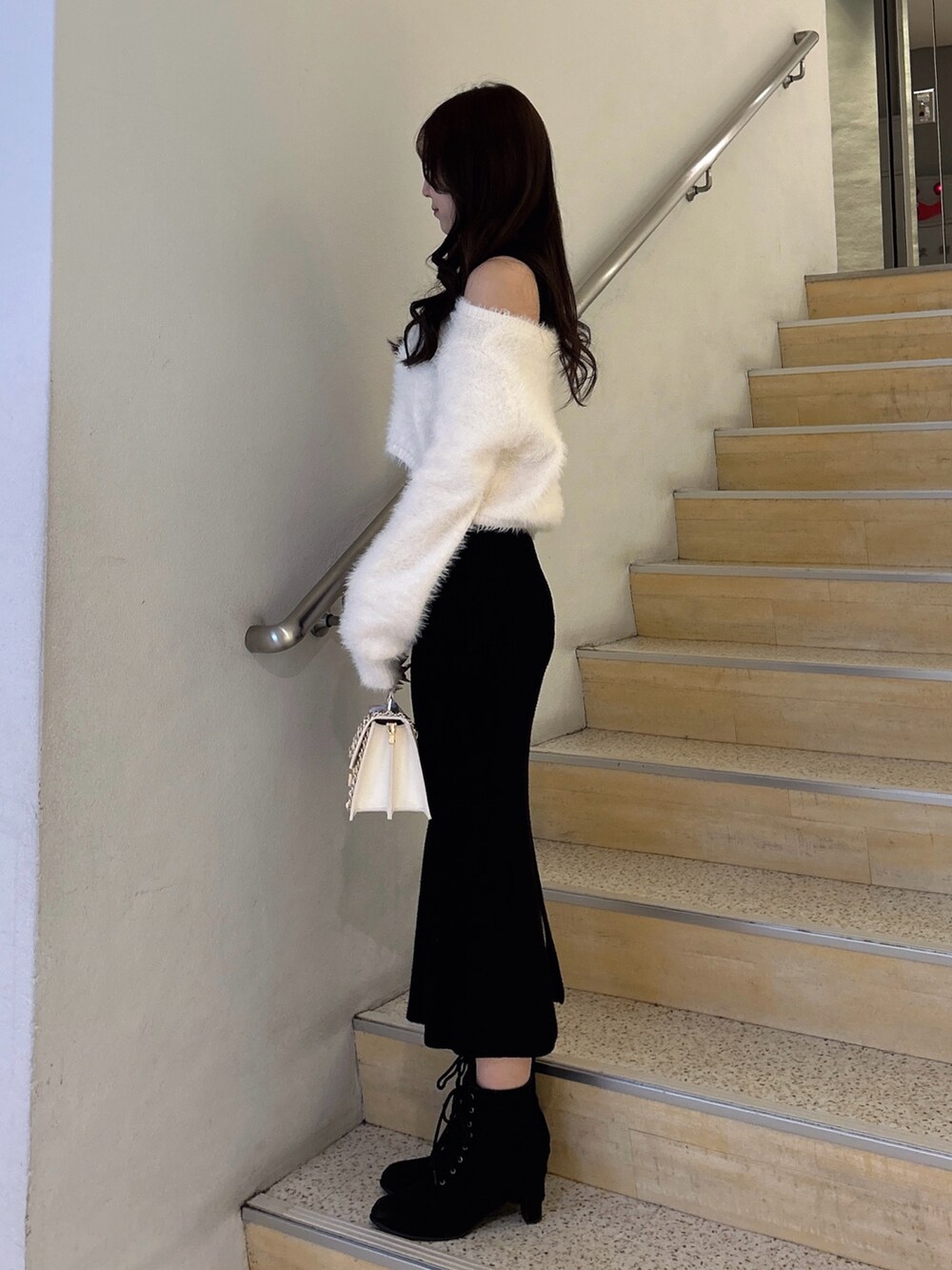 ブラック系のワンピース、ホワイト系のハンドバッグを着用したレディースの冬コーディネートの2枚目の写真