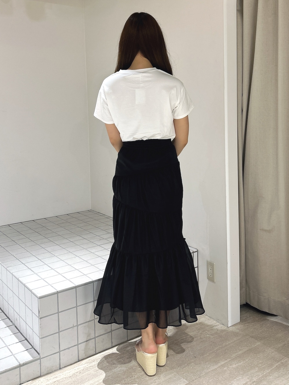 ブラック系のスカート、ホワイト系のTシャツ/カットソー、ホワイト系のサンダルを着用したレディースの夏コーディネートの4枚目の写真