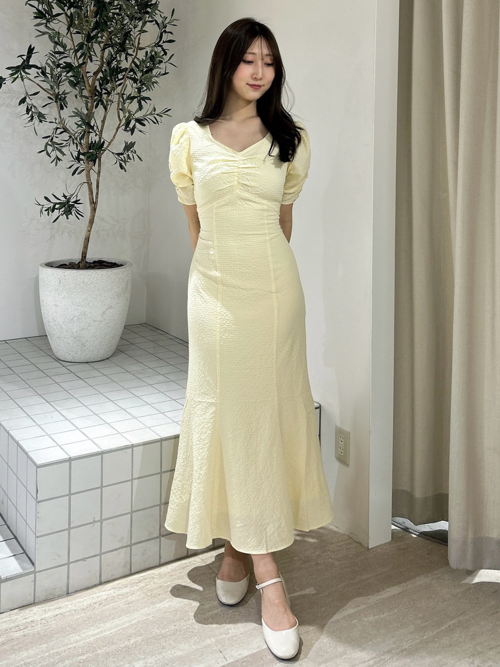 イエロー系のワンピース、ホワイト系のライダースジャケットを着用したレディースの春コーディネートの2枚目の写真