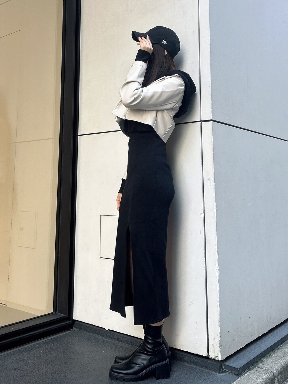 ブラック系のワンピース、ホワイト系のライダースジャケット、ブラック系のキャップを着用したレディースの秋コーディネートの2枚目の写真