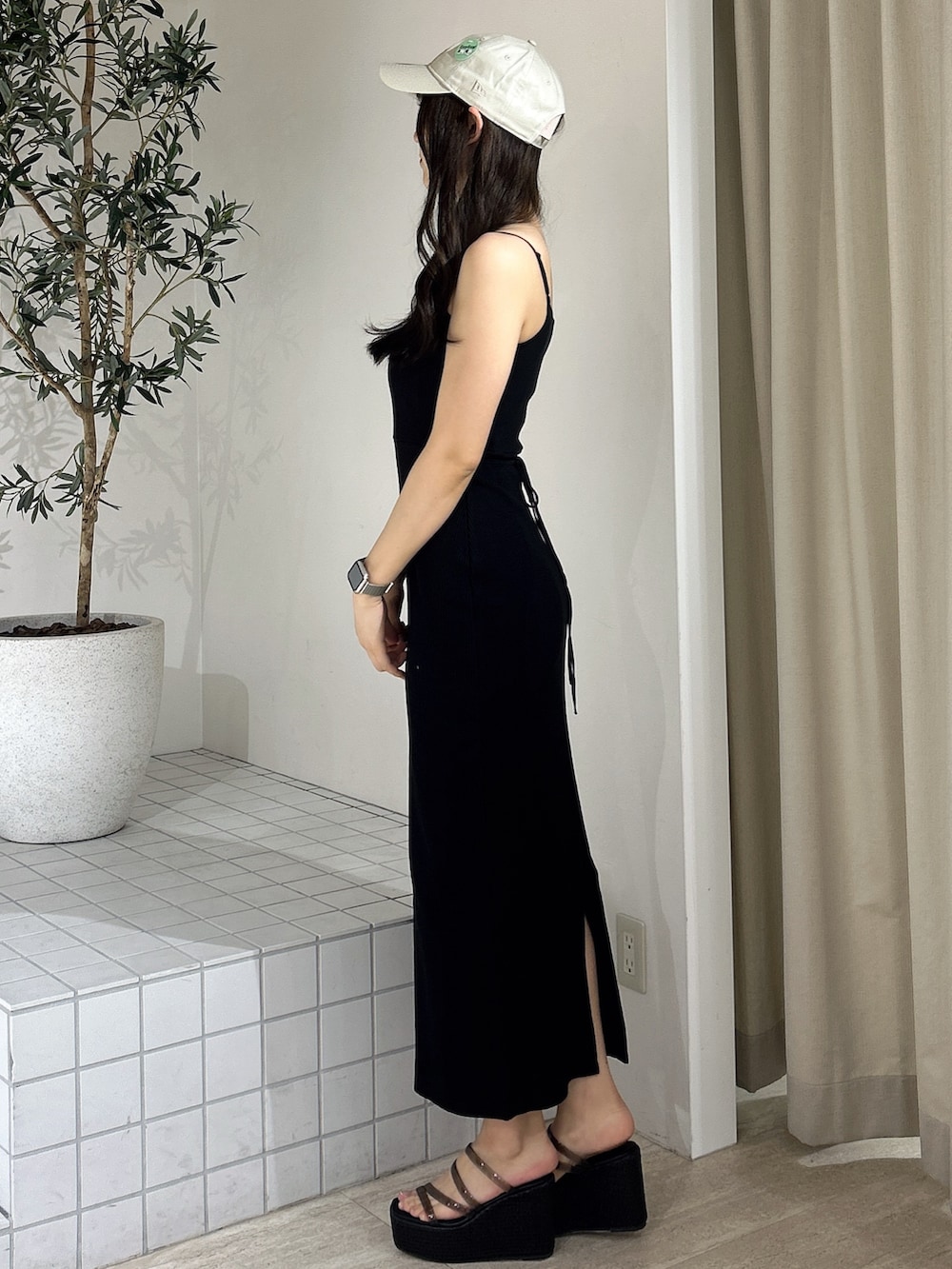 ブラック系のワンピース、ブラック系のサンダル、ベージュ系のキャップを着用したレディースの夏コーディネートの4枚目の写真