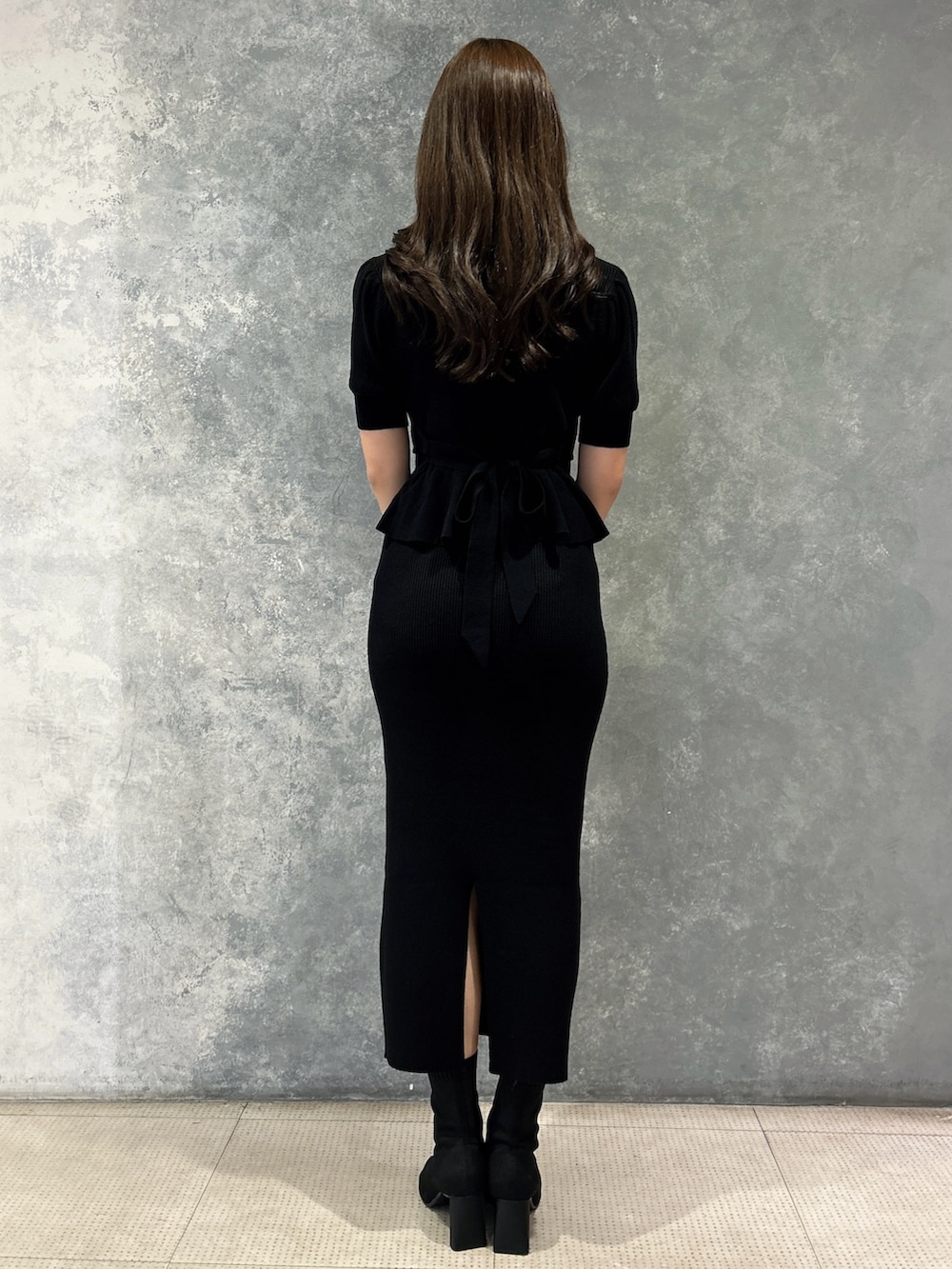 ブラック系のスカート、ブラック系のニット/セーター、ブラック系のハンドバッグを着用したレディースの春コーディネートの3枚目の写真