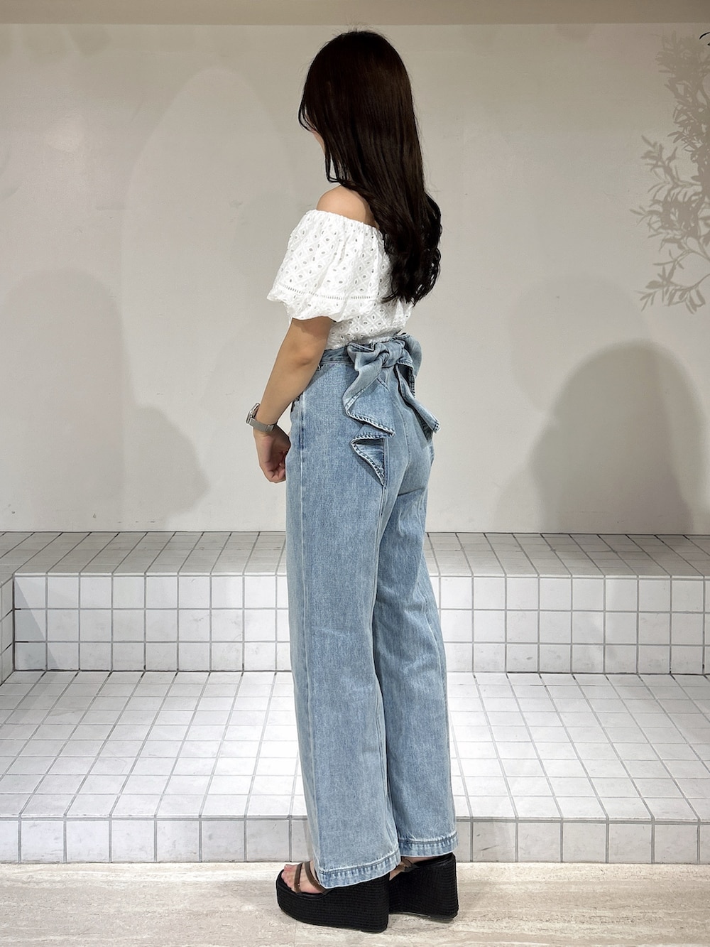 ブルー系のデニムパンツ、ブラック系のサンダル、ホワイト系のシャツ/ブラウスを着用したレディースの夏コーディネートの3枚目の写真