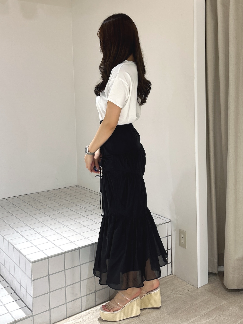 ブラック系のスカート、ホワイト系のTシャツ/カットソー、ホワイト系のサンダルを着用したレディースの夏コーディネートの3枚目の写真