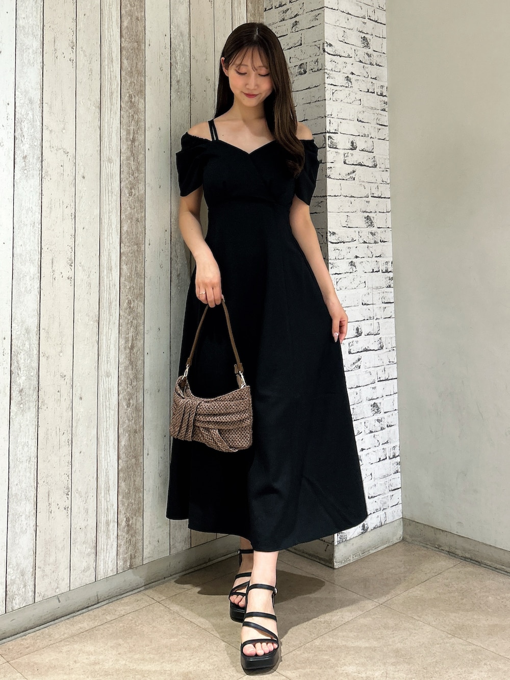 ブラック系のワンピース、ブラウン系のハンドバッグを着用したレディースの夏コーディネートの2枚目の写真