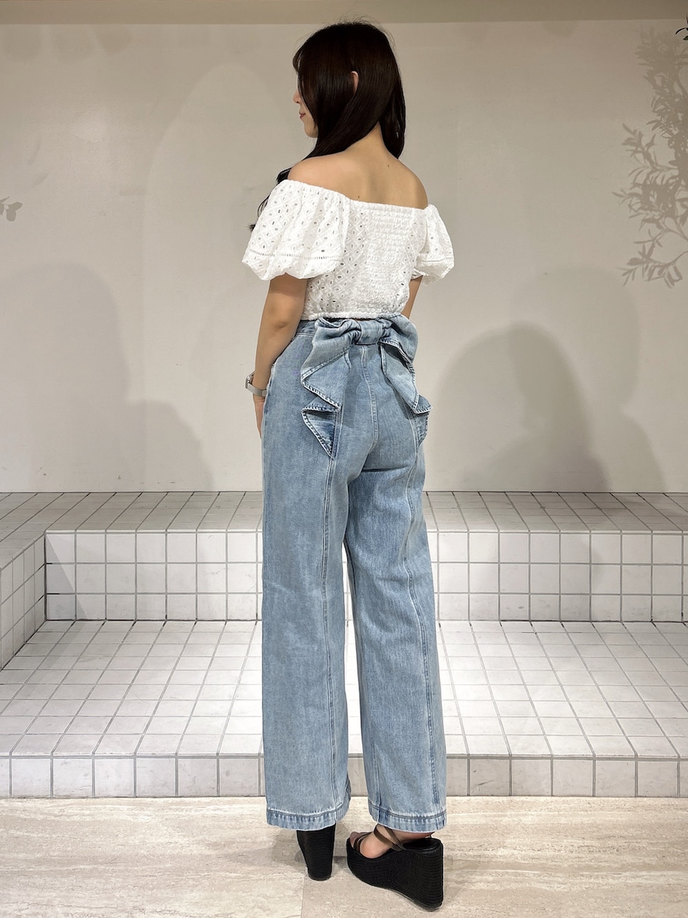 ブルー系のデニムパンツ、ブラック系のサンダル、ホワイト系のシャツ/ブラウスを着用したレディースの夏コーディネートの4枚目の写真