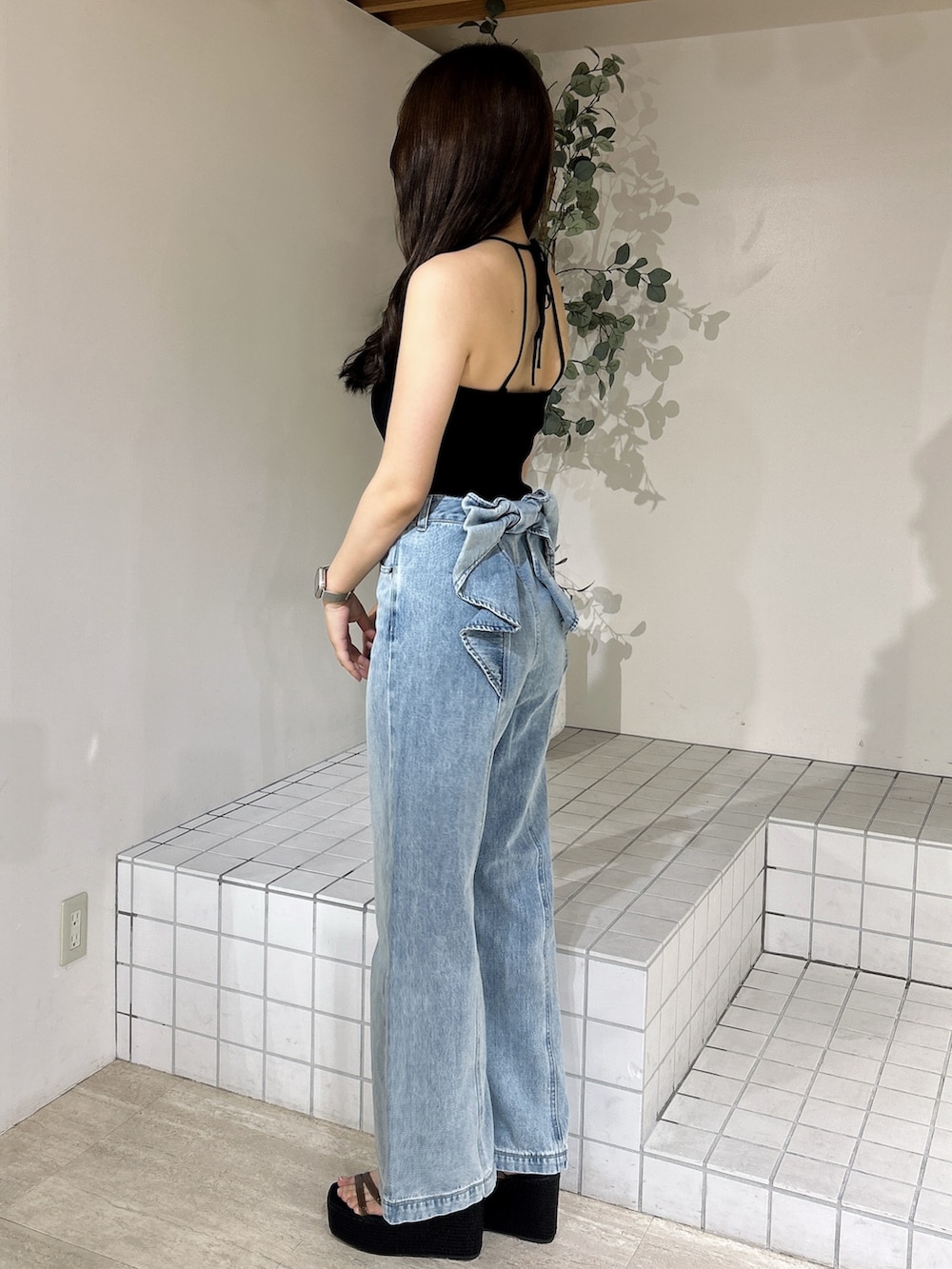 ブルー系のデニムパンツ、ブラック系のキャミソール、ブラック系のサンダルを着用したレディースの夏コーディネートの3枚目の写真