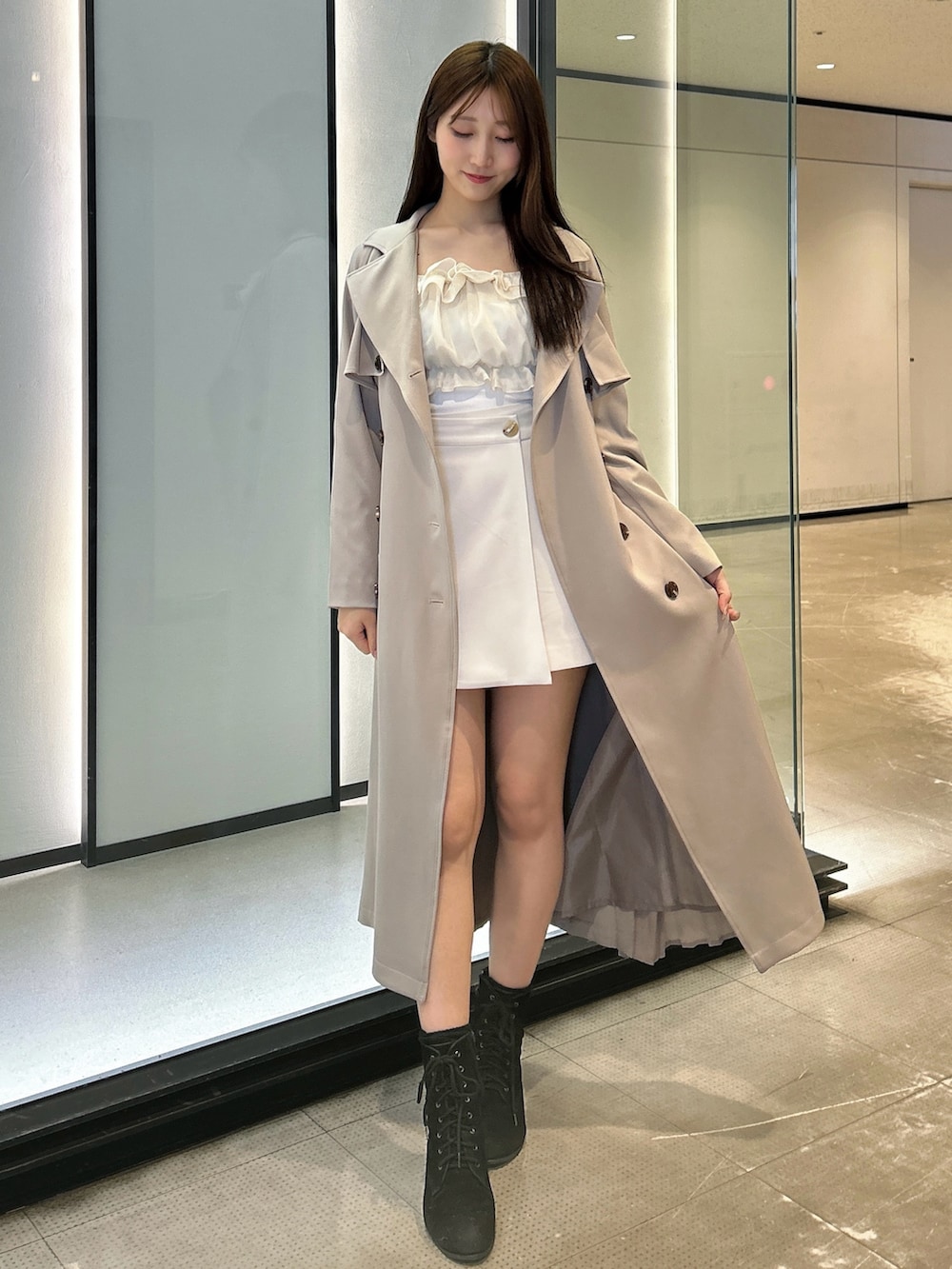 ホワイト系のスカート、ホワイト系のTシャツ/カットソー、ベージュ系のトレンチコートを着用したレディースの春コーディネートの2枚目の写真