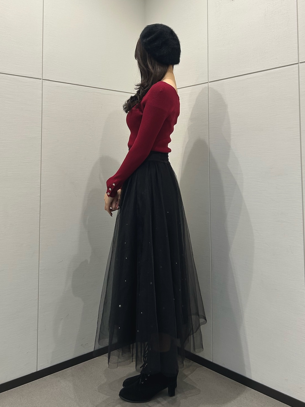 ブラック系のスカート、レッド系のニット/セーター、ブラック系のハンドバッグを着用したレディースの冬コーディネートの2枚目の写真