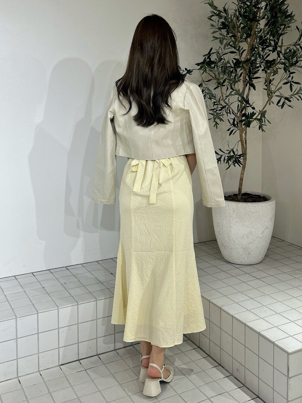 イエロー系のワンピース、ホワイト系のライダースジャケットを着用したレディースの春コーディネートの5枚目の写真