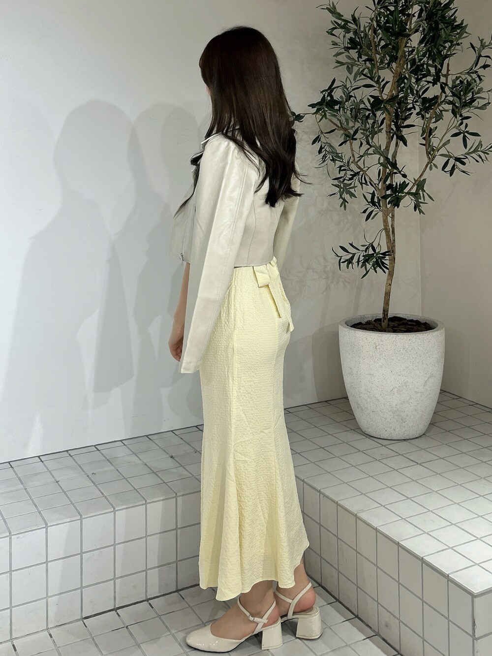 イエロー系のワンピース、ホワイト系のライダースジャケットを着用したレディースの春コーディネートの4枚目の写真