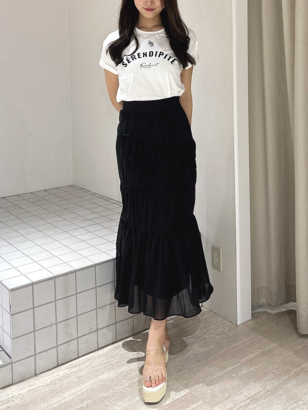 ブラック系のスカート、ホワイト系のTシャツ/カットソー、ホワイト系のサンダルを着用したレディースの夏コーディネートの5枚目の写真