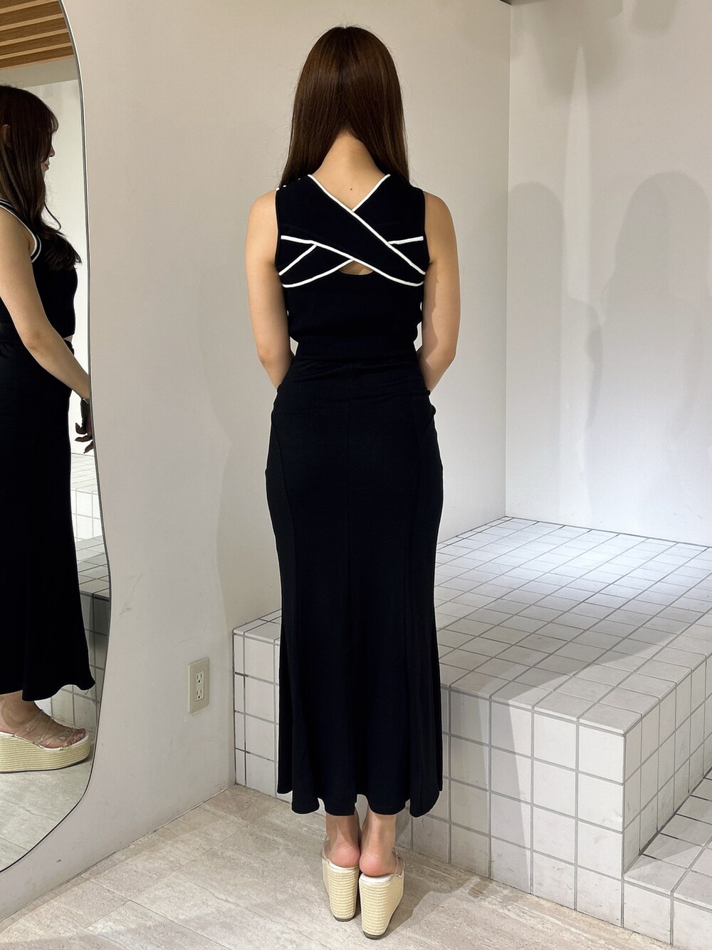 ブラック系のスカート、ホワイト系のサンダル、ブラック系のタンクトップを着用したレディースの夏コーディネートの3枚目の写真