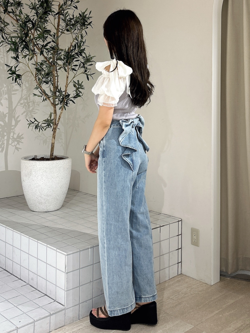 ブルー系のデニムパンツ、ブルー系のニット/セーター、ブラック系のサンダルを着用したレディースの夏コーディネートの4枚目の写真