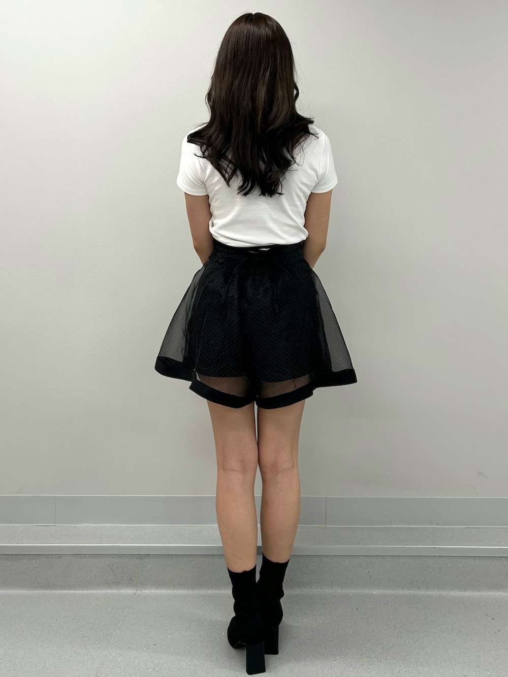 ブラック系のスカート、ホワイト系のTシャツ/カットソーを着用したレディースの春コーディネートの3枚目の写真