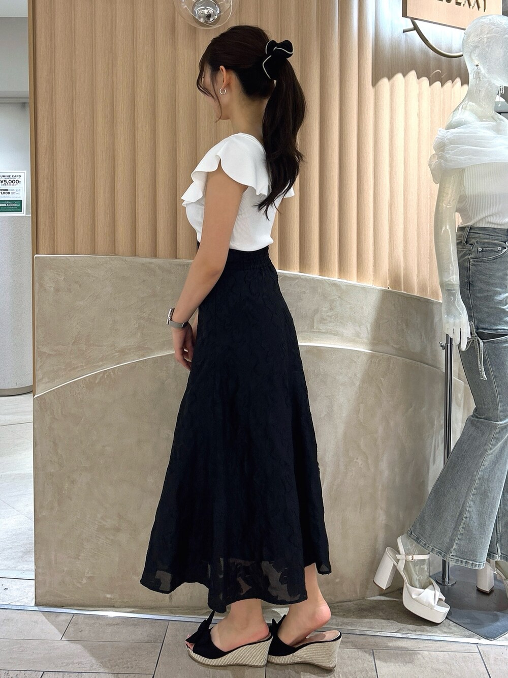 ブラック系のスカート、ホワイト系のニット/セーターを着用したレディースの夏コーディネートの3枚目の写真